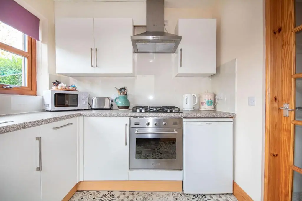 a kitchen with white cabinets and a stove top oven at Innes Street Apartments in Inverness
