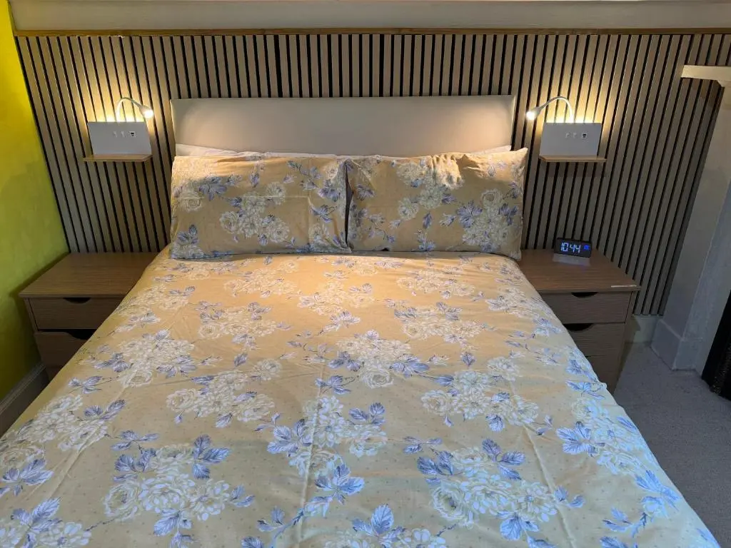 a bed in a bedroom with two nightstands and a bedspread with blue at Harbour House Bed & Breakfast - Wick in Wick