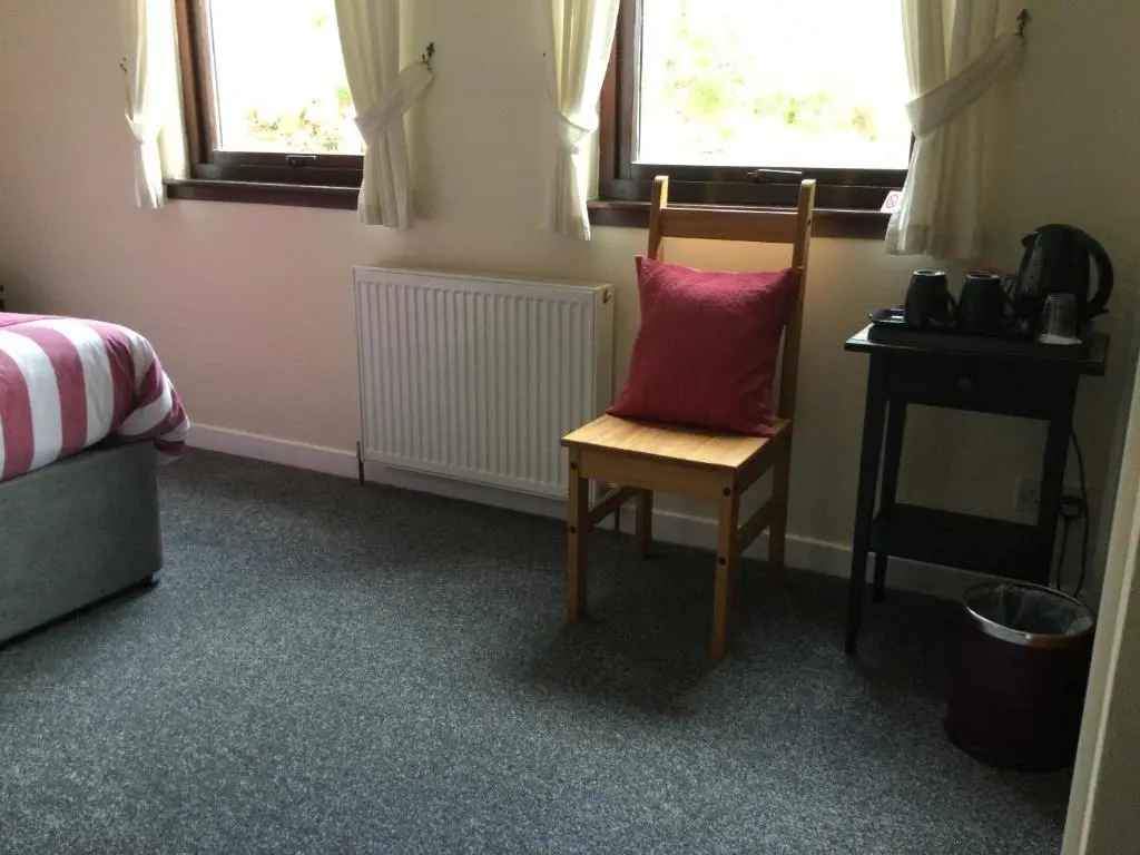 a chair with a red pillow sitting in a room at Darroch View B&B in Invermoriston