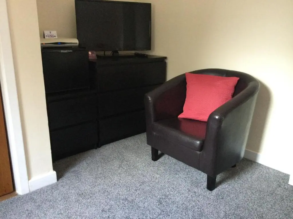 a chair with a red pillow sitting next to a dresser at Darroch View B&B in Invermoriston