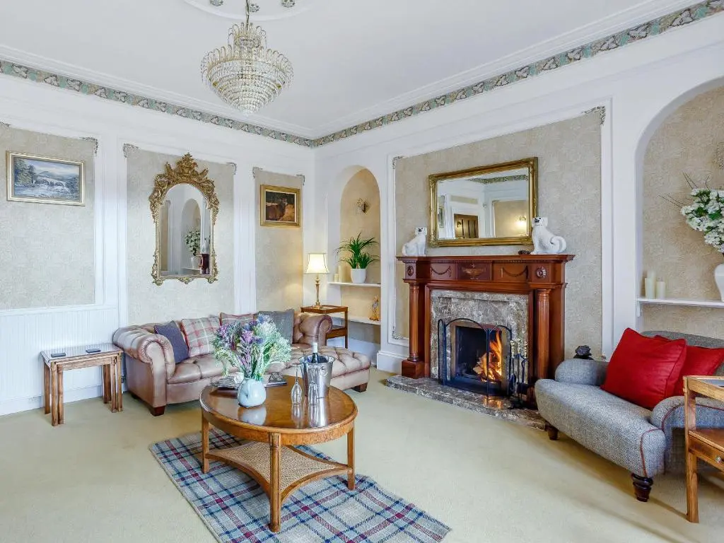 a living room with a couch and a fireplace at Craigendarroch House in Ballater