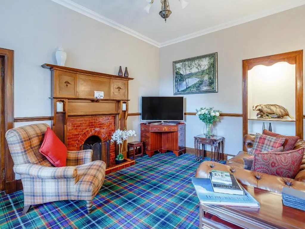 a living room with a couch and a fireplace at Craigendarroch House in Ballater