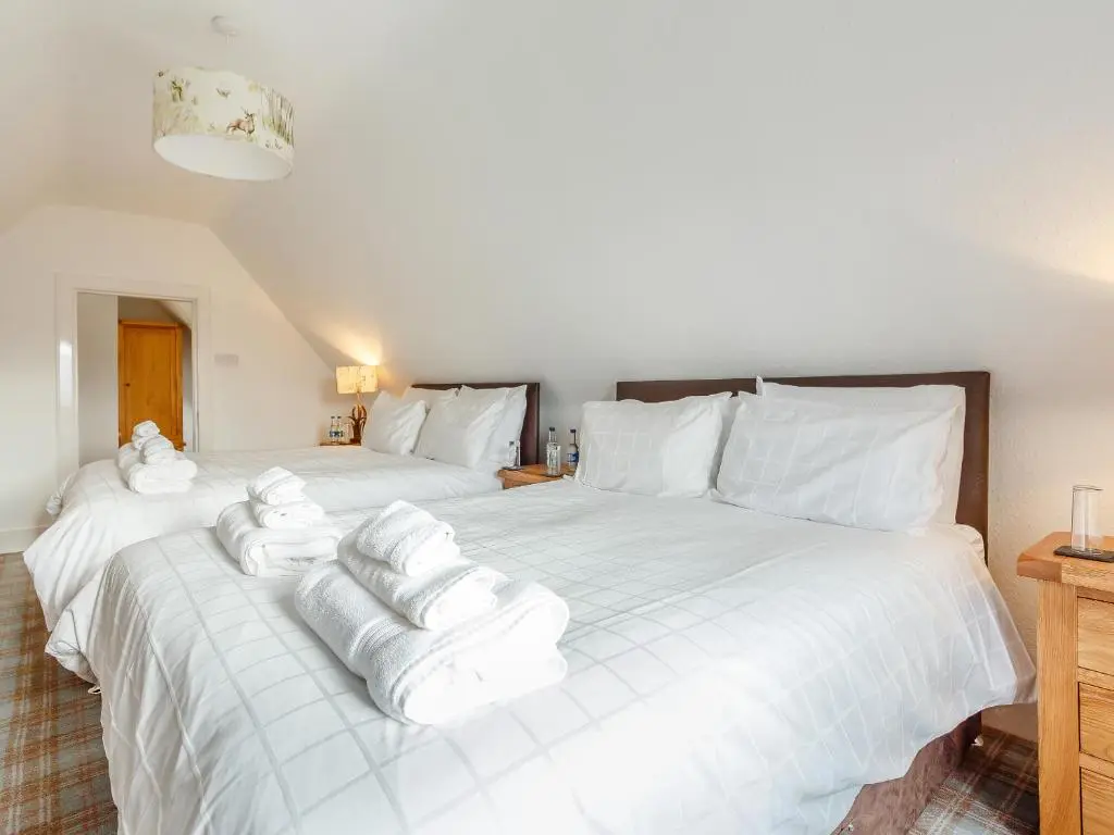 two beds in a room with white towels on them at Craigendarroch House in Ballater