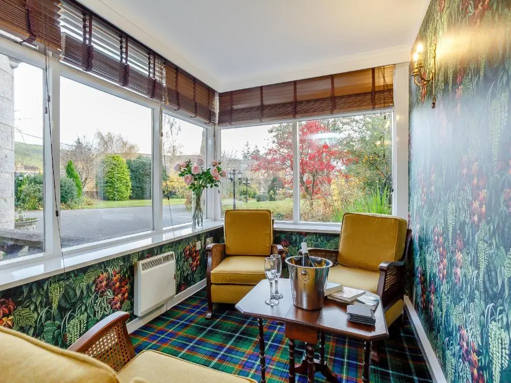 a room with two chairs and a table and windows at Craigendarroch House in Ballater