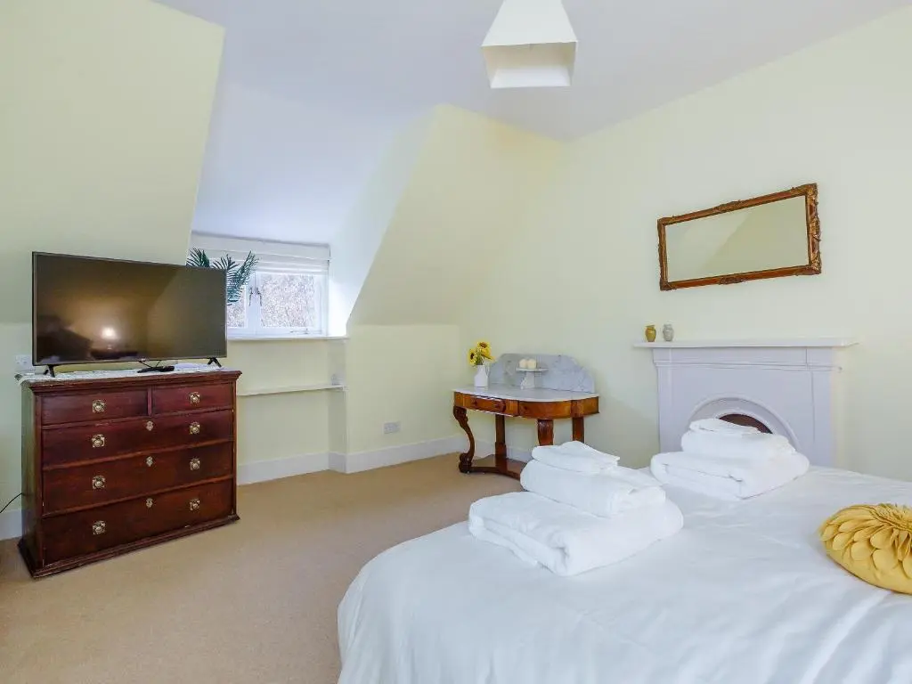 a bedroom with two beds with a television and a dresser at Craigendarroch House in Ballater