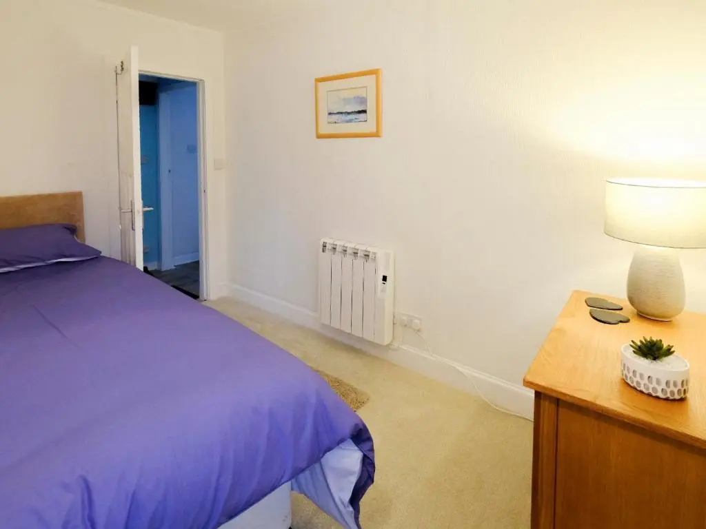 a bedroom with a bed and a table with a lamp at Fisher's Cottage in Balintore