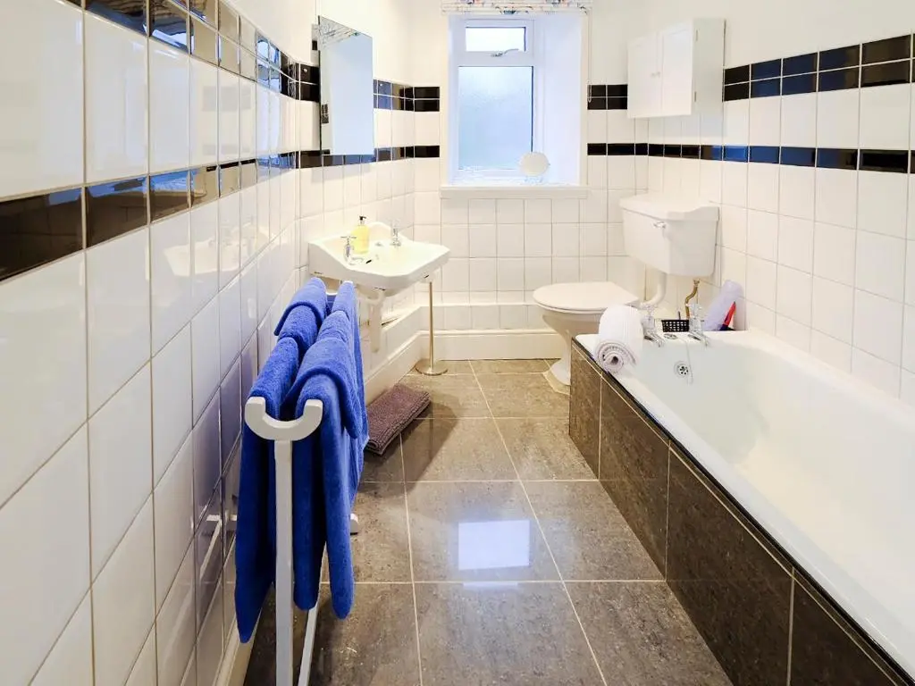 a bathroom with a tub and a sink and a toilet at Fisher's Cottage in Balintore