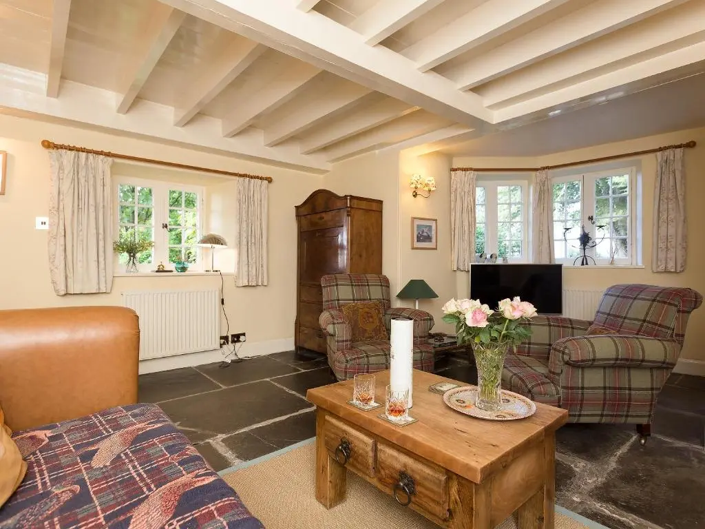 a living room with couches and a table with flowers on it at Big Barns Cottage in Backies
