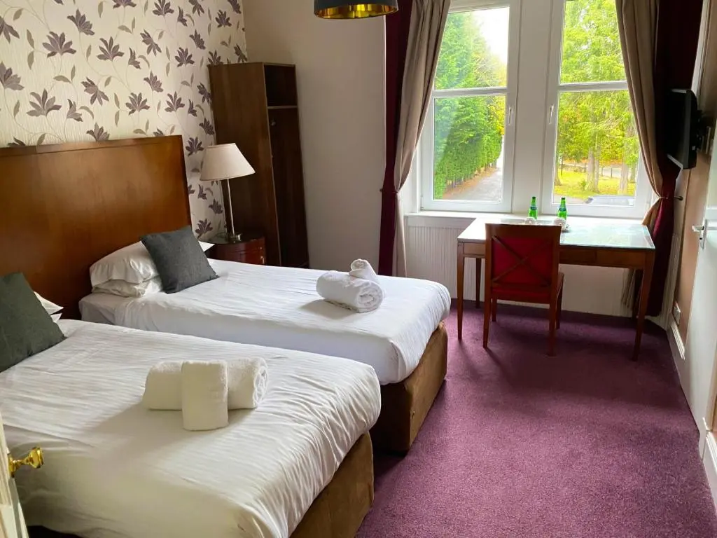 a hotel room with two beds and a window at The Speyside Hotel and Restaurant in Grantown on Spey