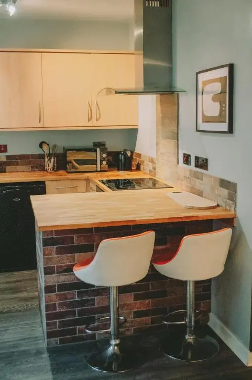 a kitchen with a counter with two white bar stools at The Black Isle Retreat in Inverness