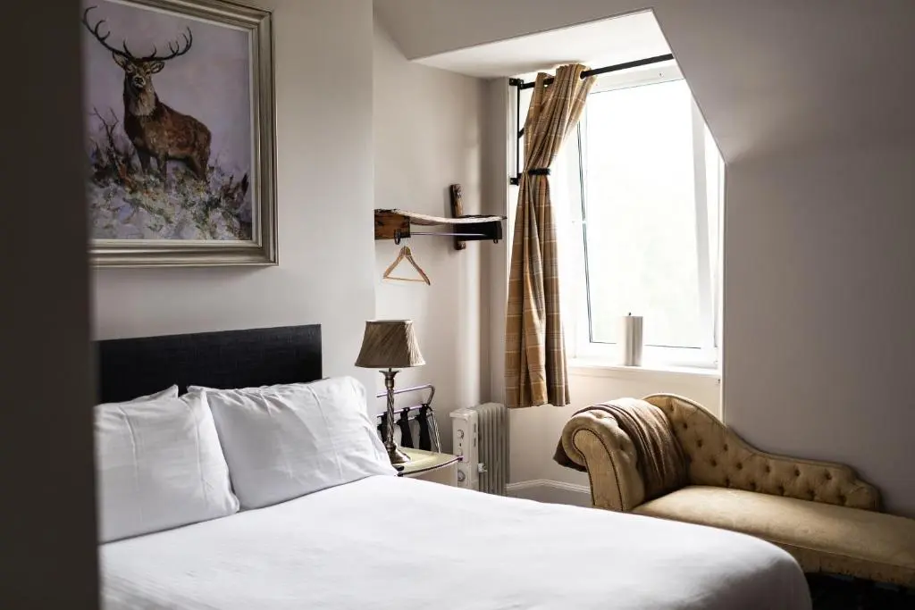 a bedroom with a bed and a chair and a window at Whitebridge Hotel in Whitebridge