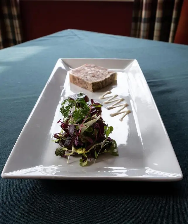 a plate with a sandwich and salad on a table at Altnaharra Hotel in Lairg