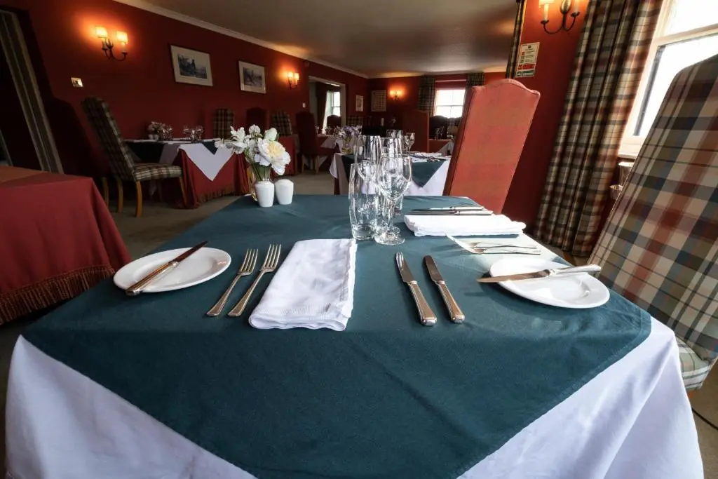 a table with a green and white table cloth on it at Altnaharra Hotel in Lairg