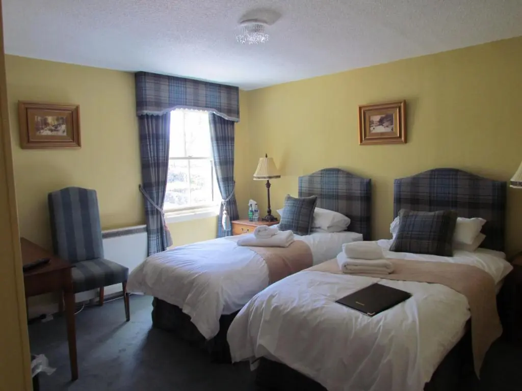 a hotel room with two beds and a desk at Altnaharra Hotel in Lairg