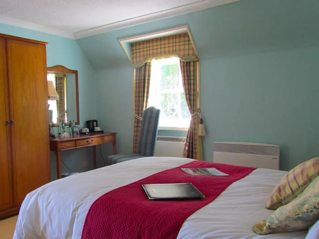 a bedroom with a bed with a red blanket at Altnaharra Hotel in Lairg