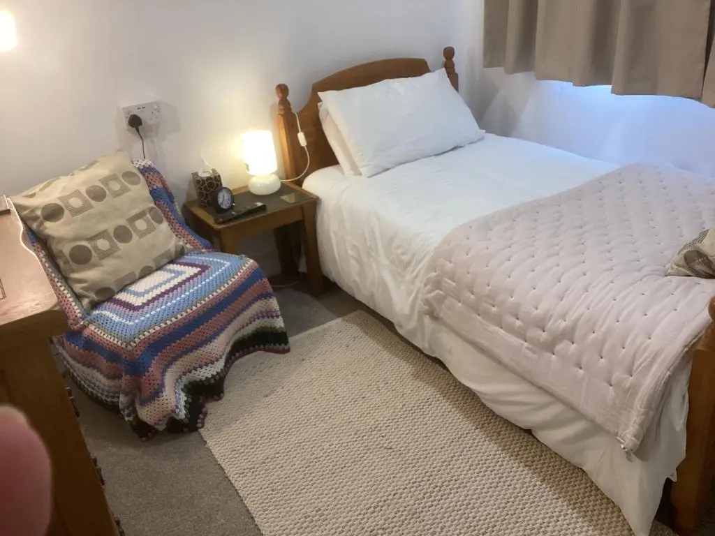 a small bedroom with a bed and a chair at Alba b & b in Inverness