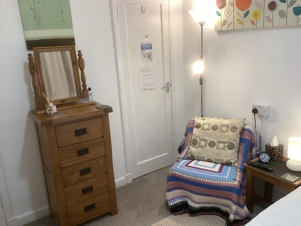 a bedroom with a dresser and a chair and a mirror at Alba b & b in Inverness