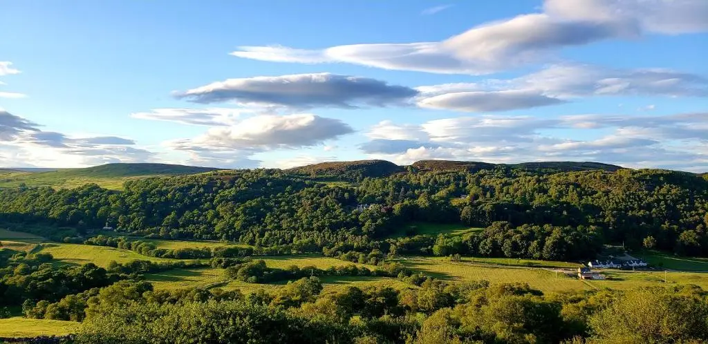 a view of a green valley with trees and clouds at Highland Glen Lodges in Rogart