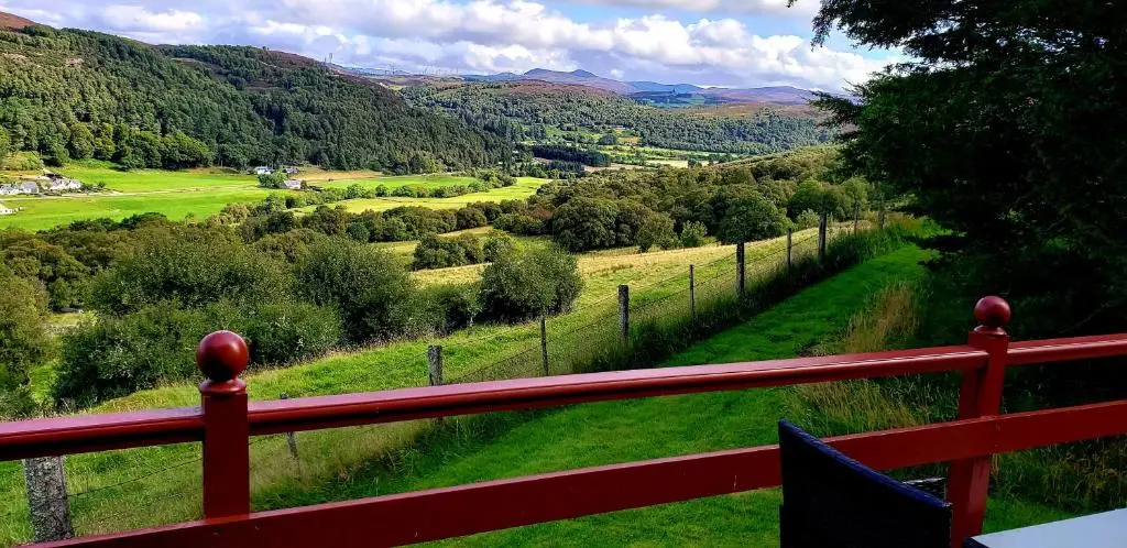 a red fence with a view of a valley at Highland Glen Lodges in Rogart