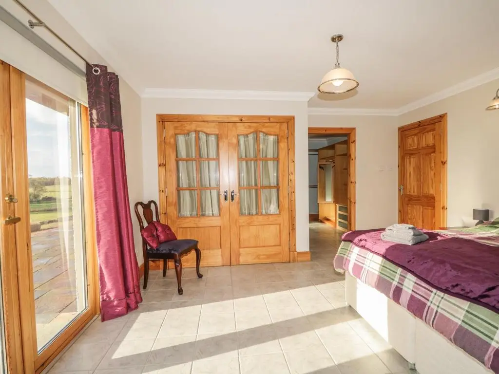 a bedroom with a bed and a sliding glass door at The Glebe in Invergordon