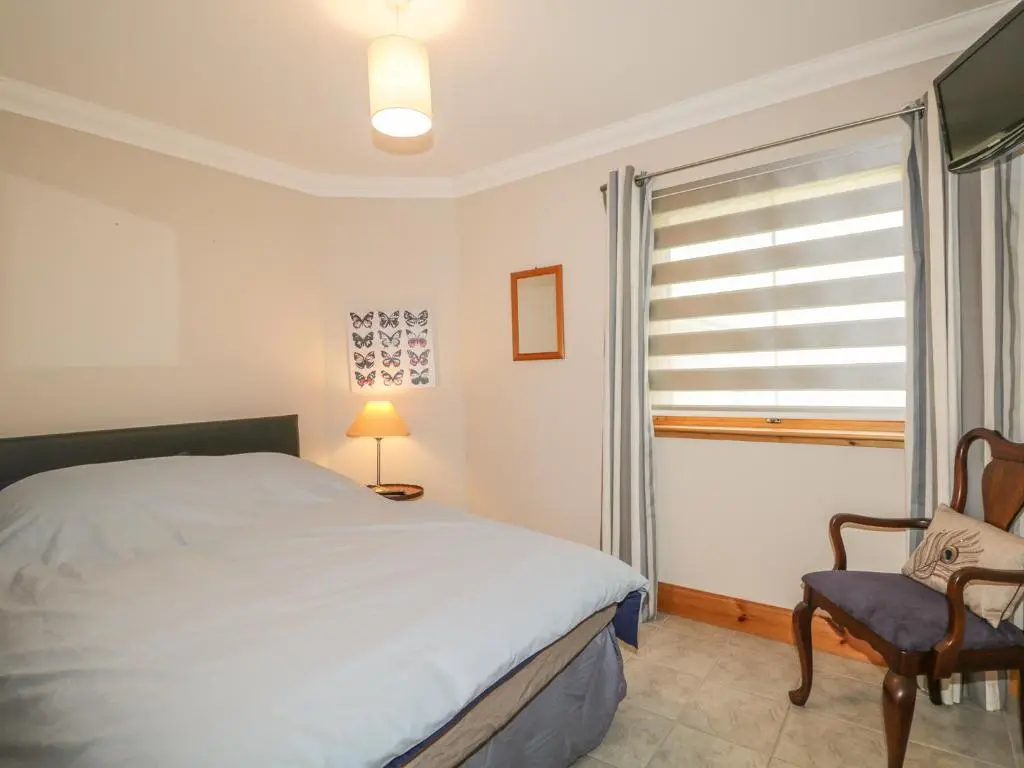 a bedroom with a bed and a chair and a window at The Glebe in Invergordon