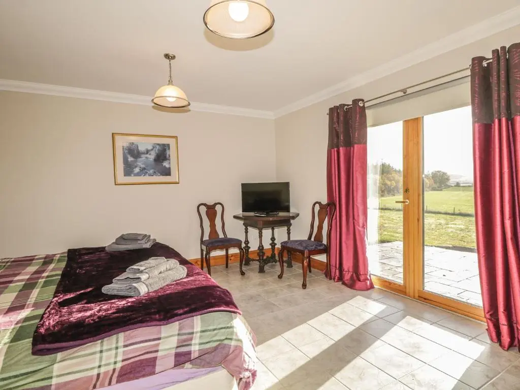 a bedroom with a bed and a desk with a television at The Glebe in Invergordon