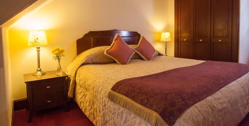 a hotel room with a bed and two lamps at Tigh na Sgiath Country House Hotel in Grantown on Spey