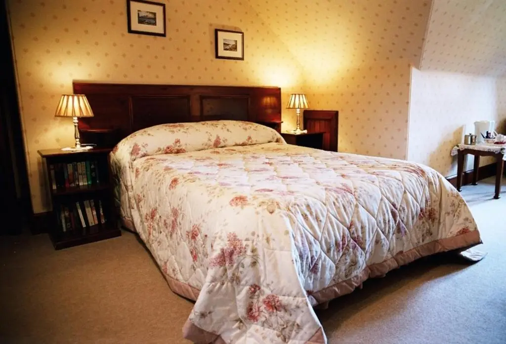 a bedroom with a bed and two tables and two lamps at Tigh na Sgiath Country House Hotel in Grantown on Spey