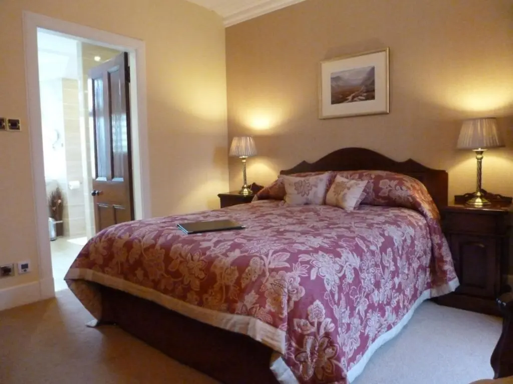 a bedroom with a large bed with a red blanket at Tigh na Sgiath Country House Hotel in Grantown on Spey