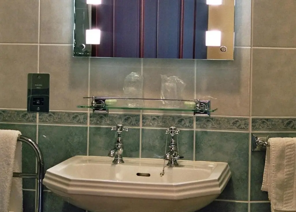 a bathroom with a sink and a mirror and towels at Tigh na Sgiath Country House Hotel in Grantown on Spey