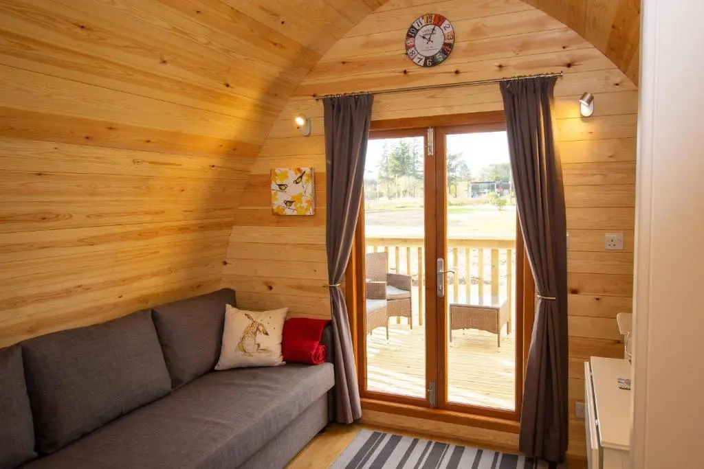 a living room with a couch and a clock on the wall at Evelix Pods Dornoch in Dornoch