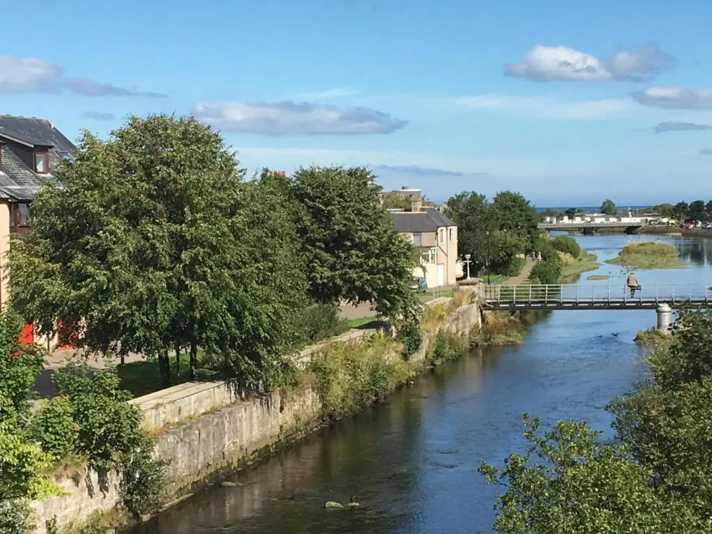 a view of a river with a bridge and buildings at Riverbank Apartments in Nairn