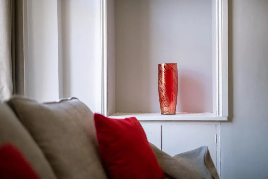 a red vase sitting on a window sill next to a couch at Dryburgh Apartments No2 in Inverness