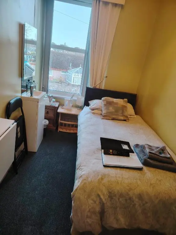 a bedroom with a bed with a book on it at Park Guest House in Inverness