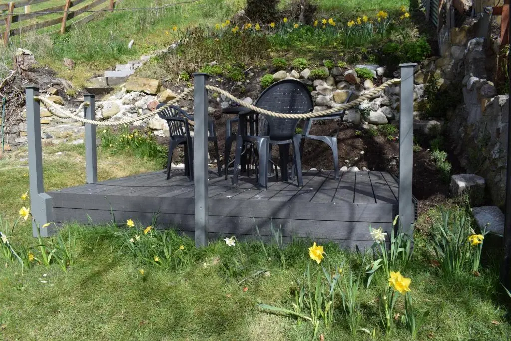 a table and chairs on a boardwalk with flowers at 3 St Gilbert Street in Dornoch