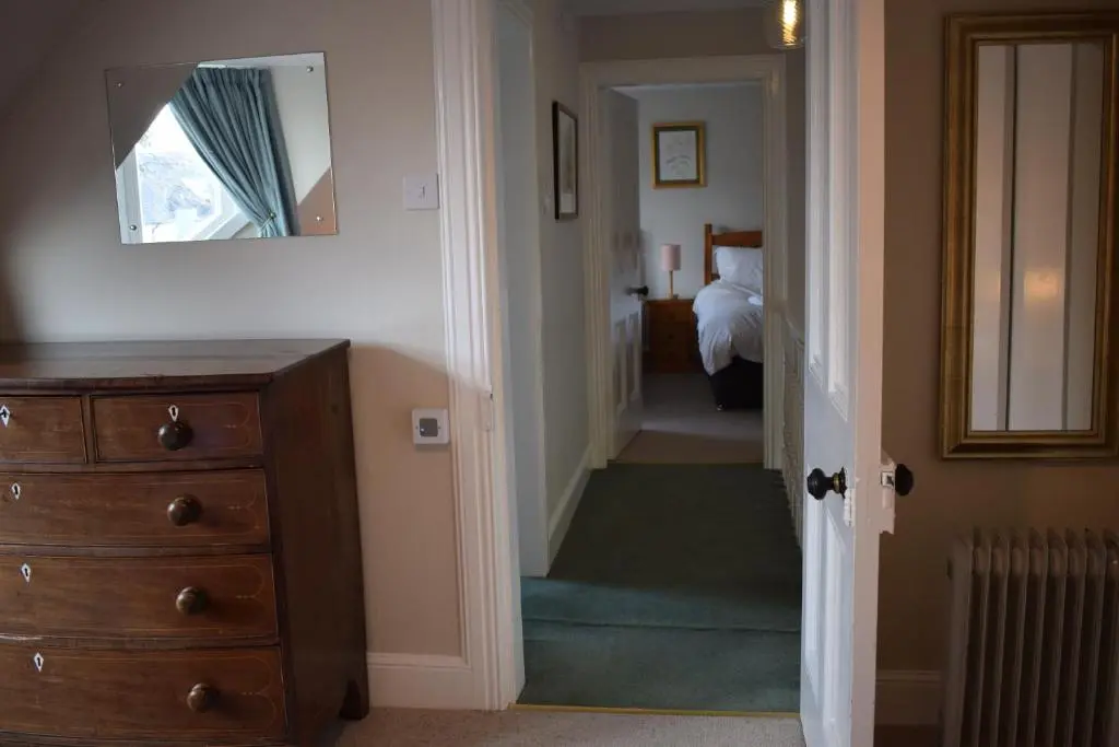 a hallway with a dresser and a mirror and a bedroom at 3 St Gilbert Street in Dornoch