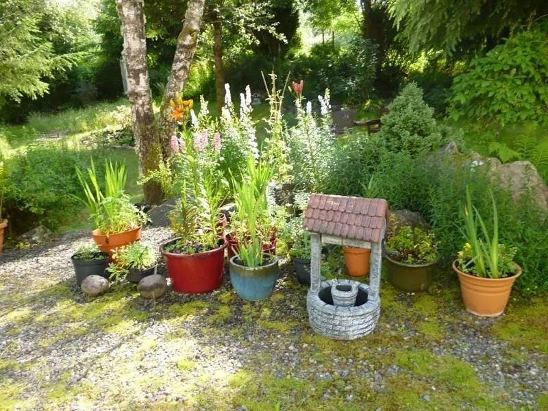 a garden with many pots of plants and a bench at Kettle House B&B in Fort Augustus