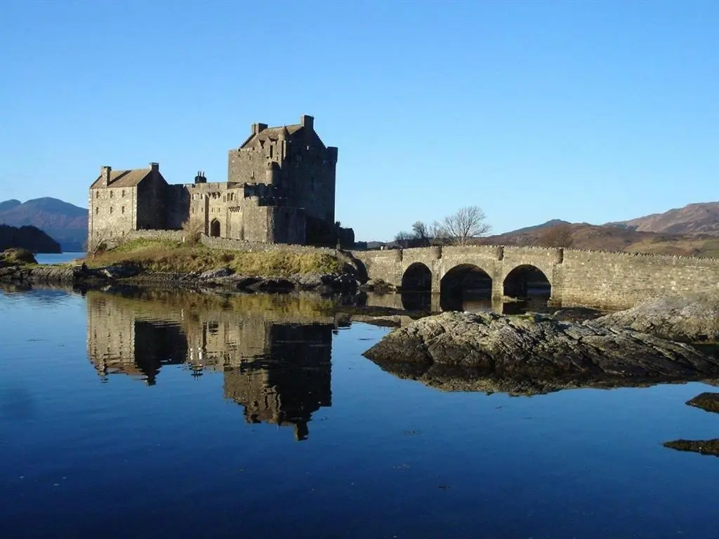 a castle sitting on the edge of a body of water at Binnilidh Mhor B&B in Glenmoriston