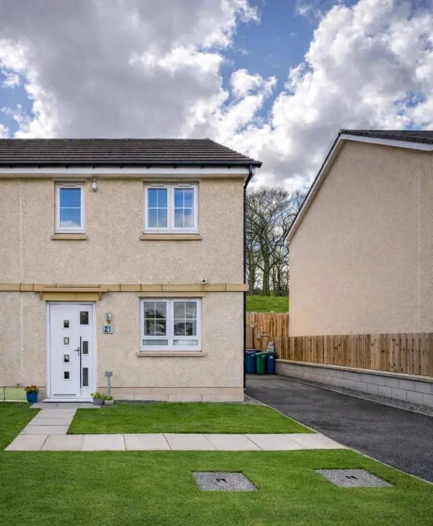 a brick house with a white door and a fence at Lily Bank House in Inverness