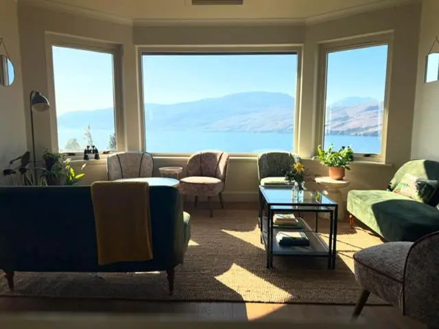 a living room with a couch and chairs and a large window at Ardvreck House in Ullapool
