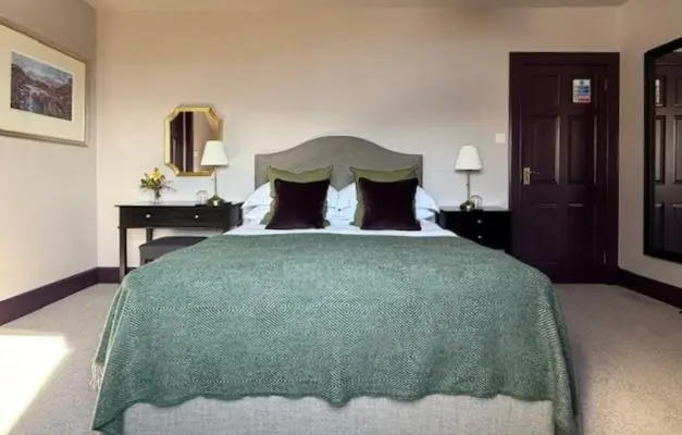 a bedroom with a large bed with a green blanket at Ardvreck House in Ullapool