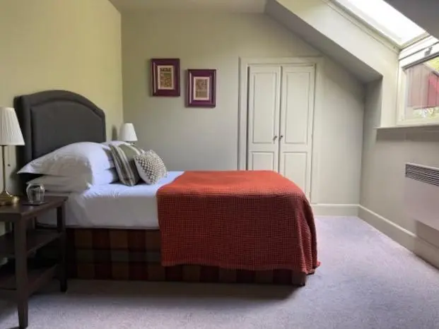 a bedroom with a bed with a red blanket on it at Ardvreck House in Ullapool