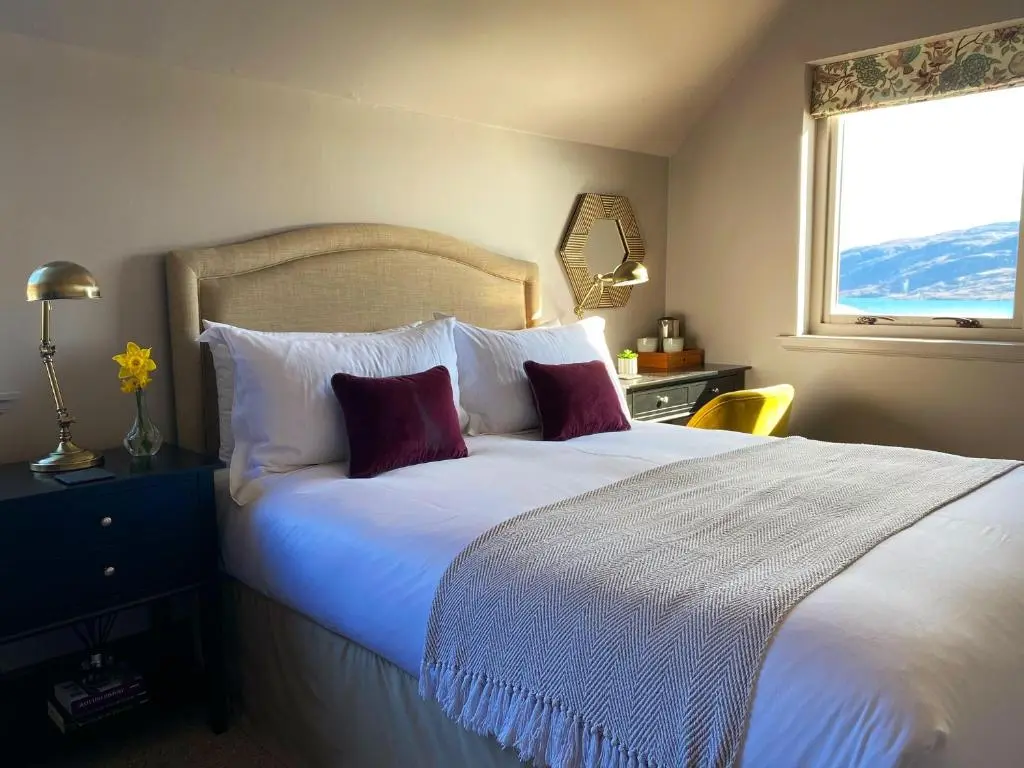 a bedroom with a large white bed with a window at Ardvreck House in Ullapool