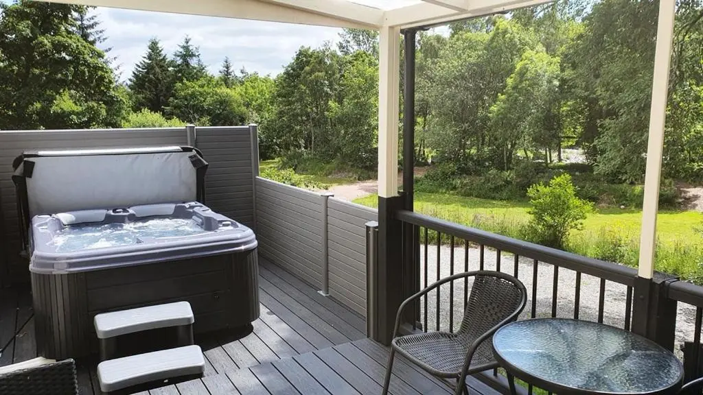 a hot tub on a deck with a table and chairs at River Cottage Hot tub spa in Drumnadrochit