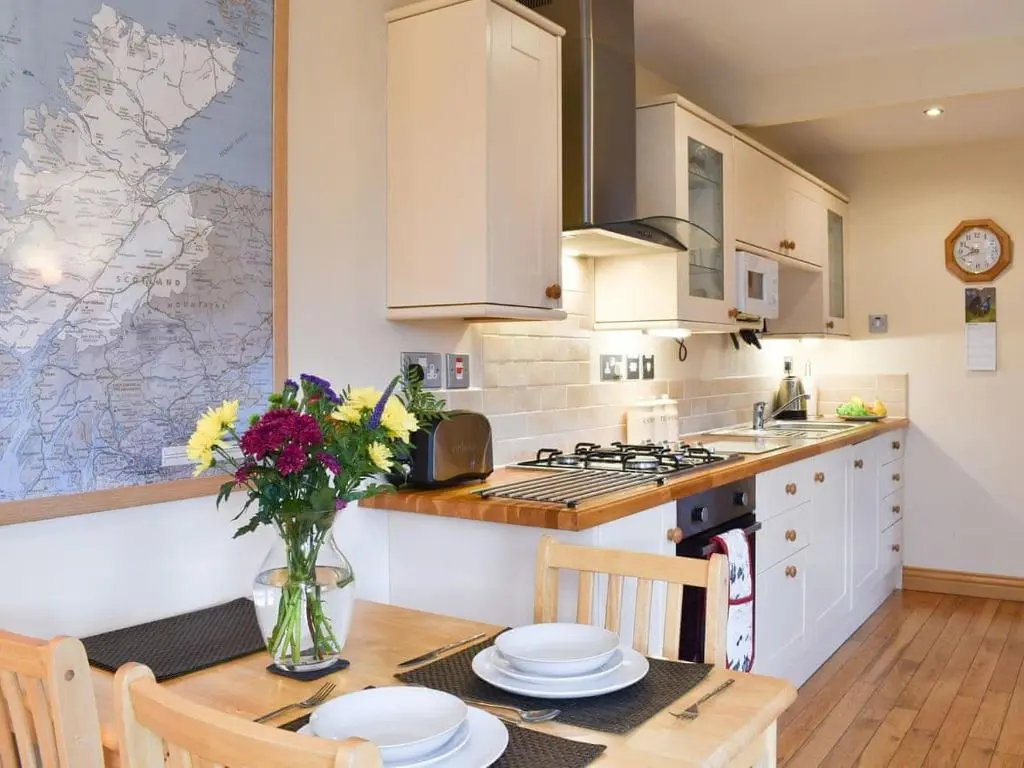 a kitchen with a table with plates and flowers on it at River Cottage Hot tub spa in Drumnadrochit