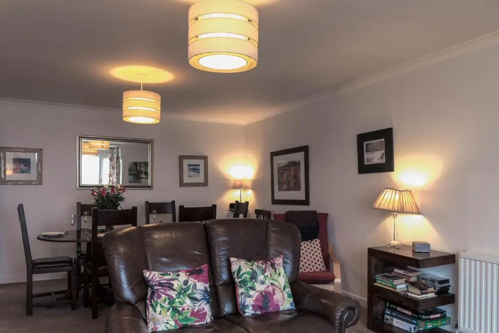 a living room with a leather couch and a table at Beachview-Holiday Flat 2- Sleeps8 in Lossiemouth