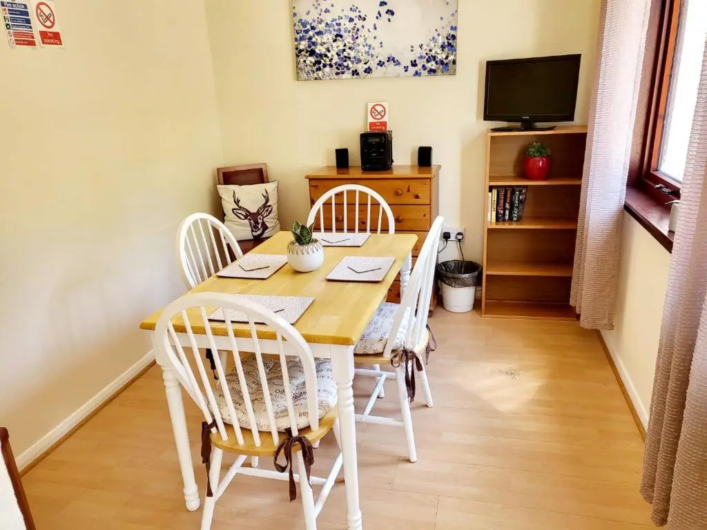 a dining room with a wooden table and chairs at Invercaul House in Inverness