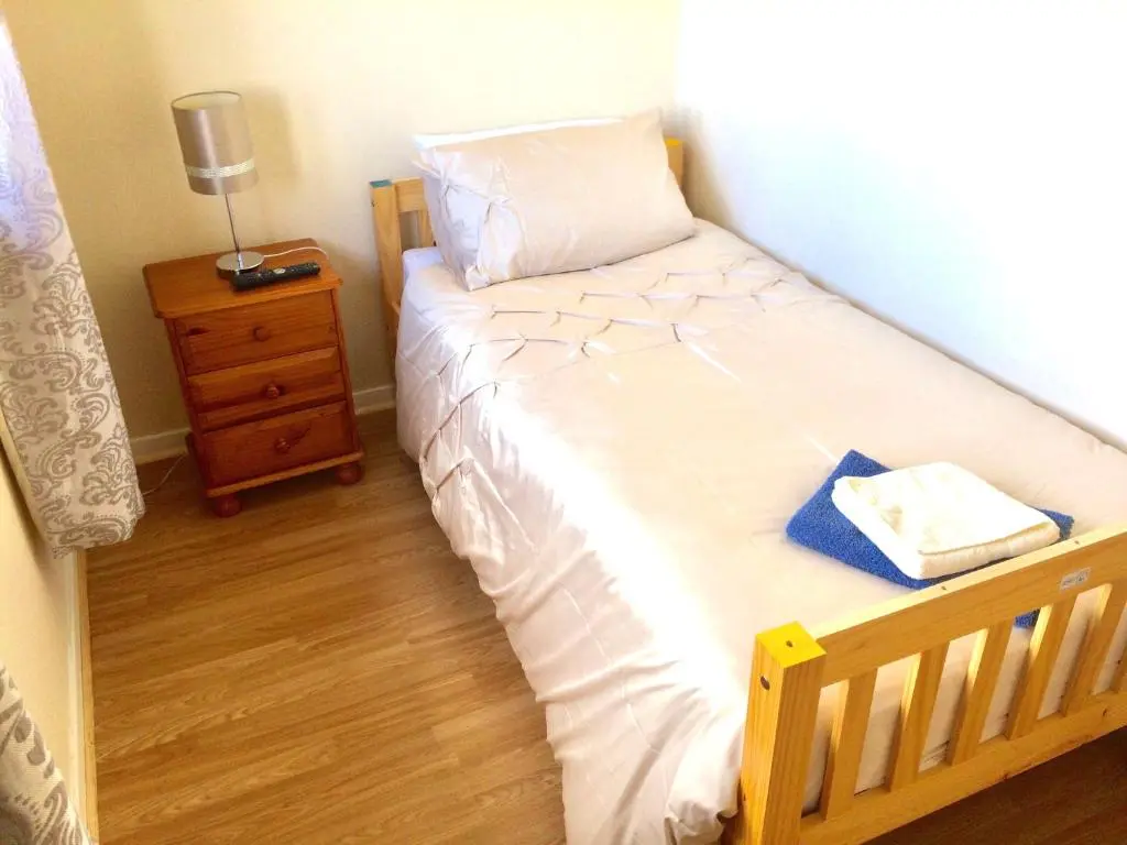 a small bedroom with a bed with a nightstand and a bed sidx sidx sidx at Invercaul House in Inverness