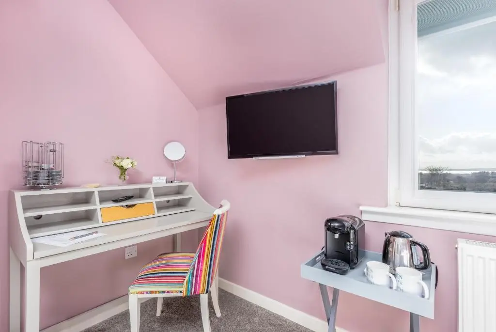 a pink room with a desk and a tv on a wall at Heartseed House Bed & Breakfast in Dornoch