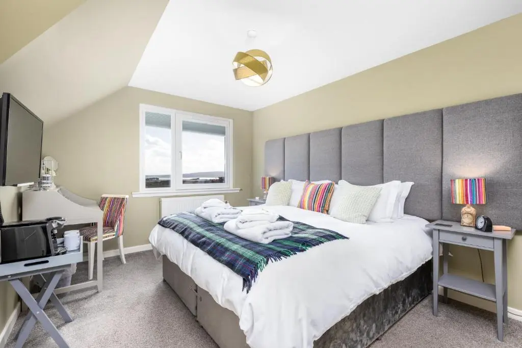 a bedroom with a large bed and a desk at Heartseed House Bed & Breakfast in Dornoch